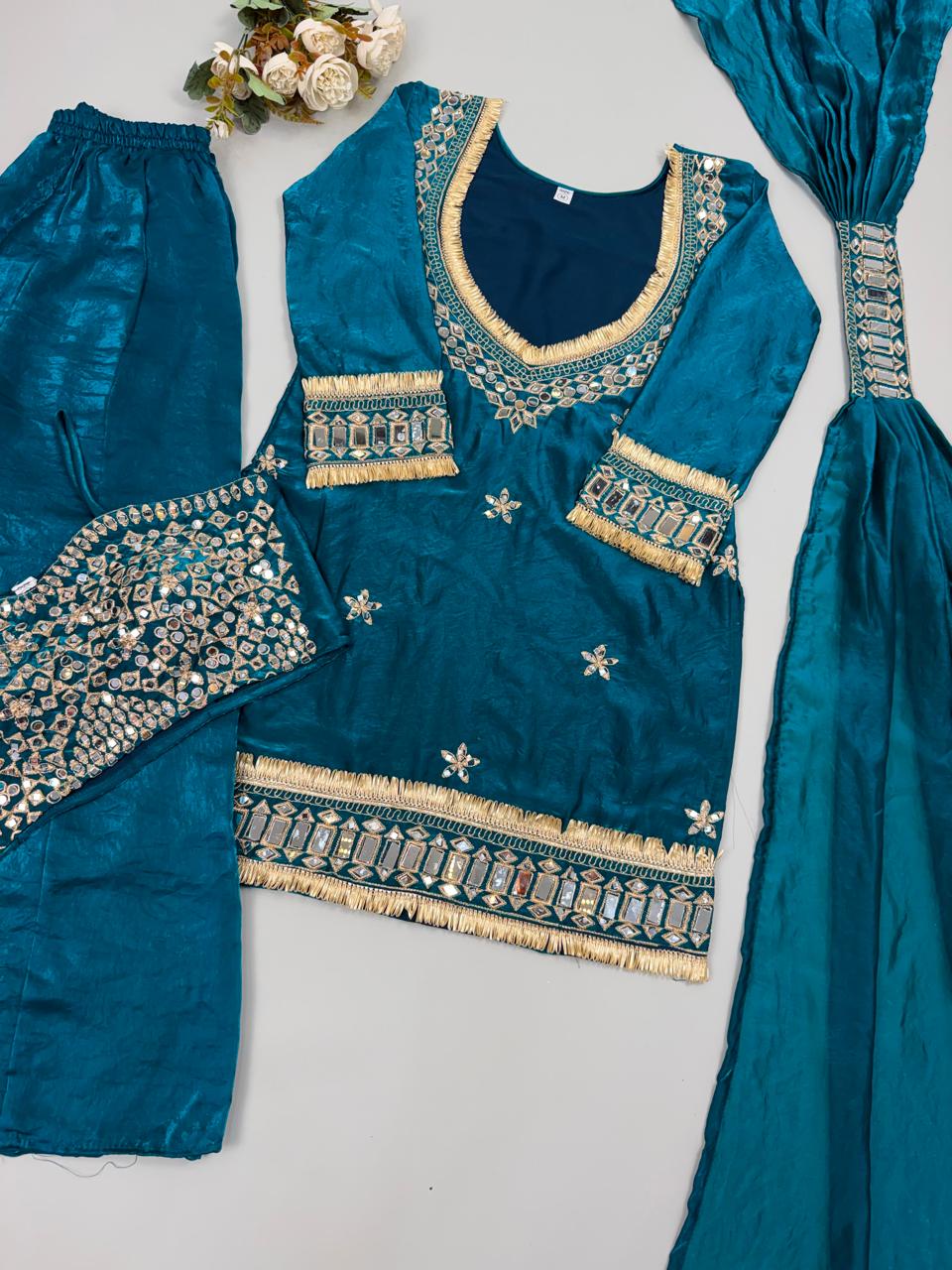 Teal traditional outfit with embroidered details on a light gray background